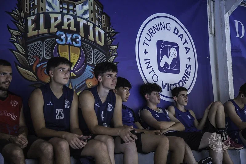 Jugadores en el banquillo con el emblema de El Patio 3x3 en la lona